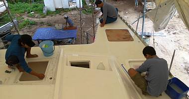 Akoosh, Pla and Ben polish the deck while Lek sands below