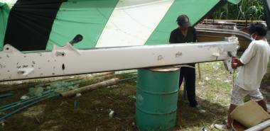 Grinding paint off our mast under the shade of a spinnaker