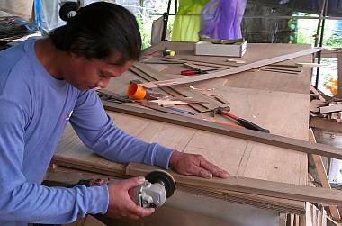 Houa happily sanding down a piece of floorboard trim