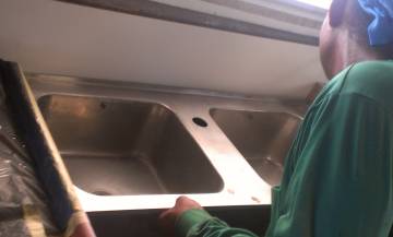 Houa positioning the new stainless steel sinks in the galley